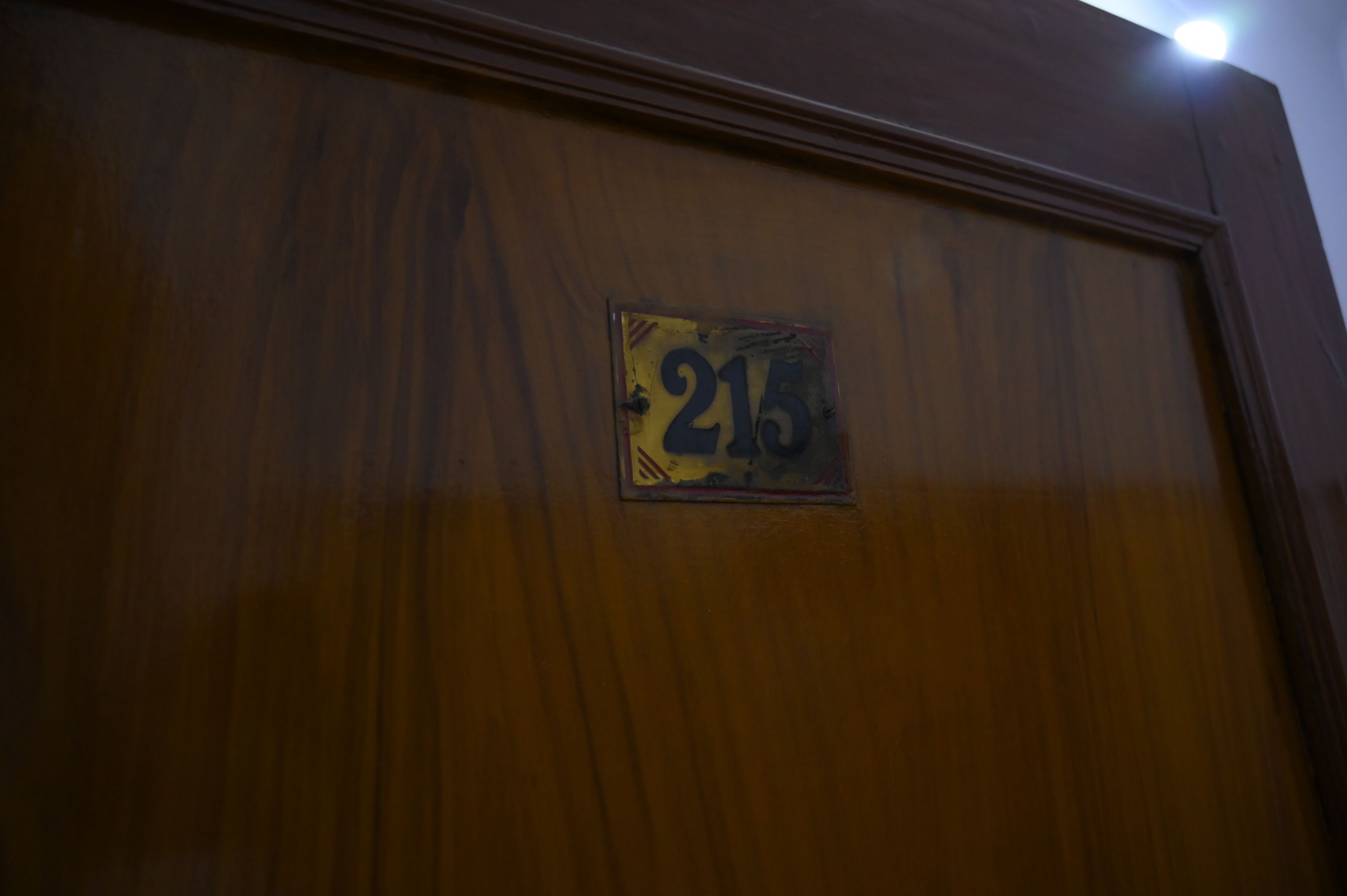 Una puerta de madera con una placa que muestra el número 215.
