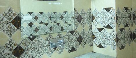 A bathroom with a white sink, a mirror, patterned tiles, and a water heater mounted on the wall.