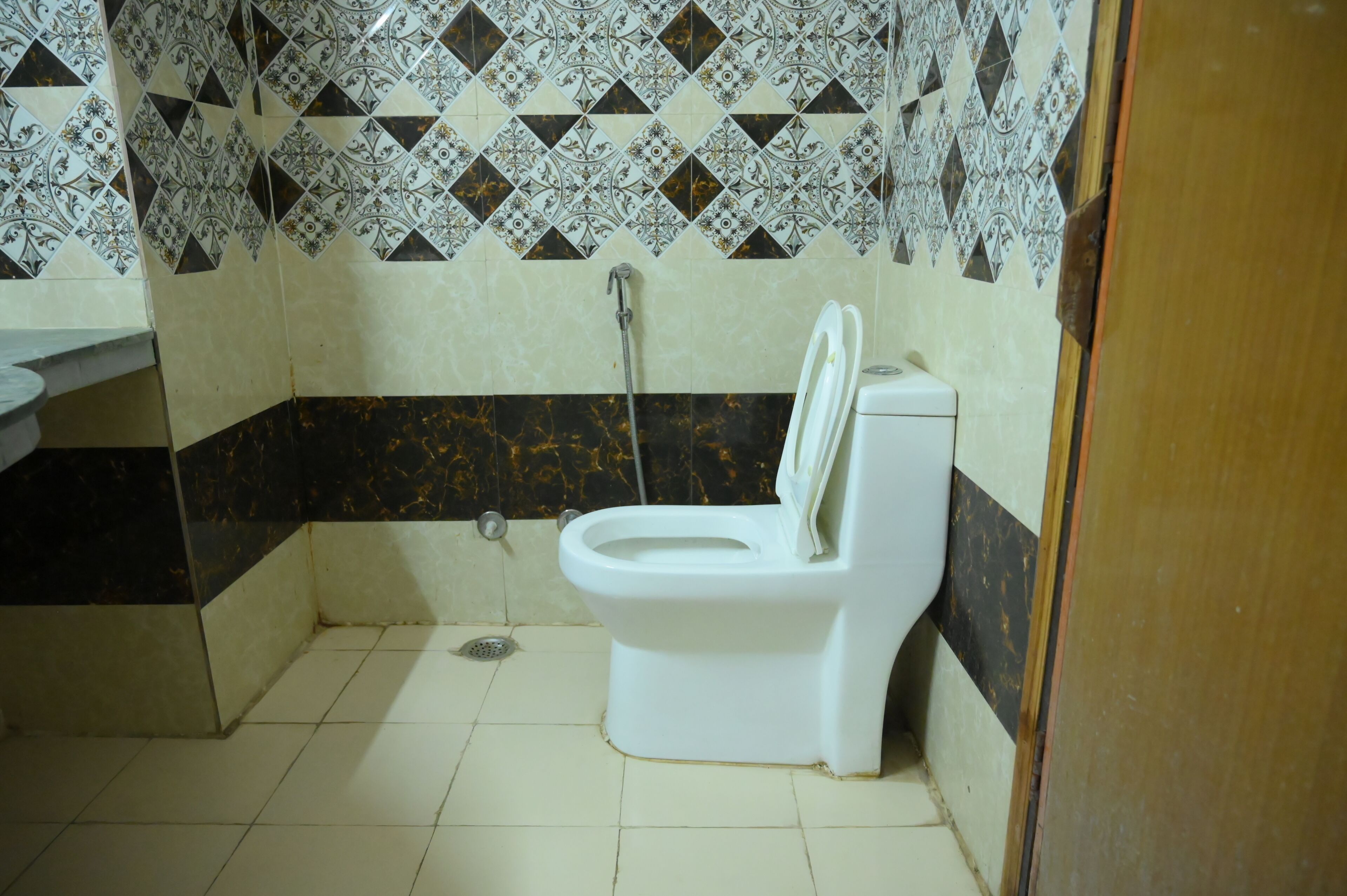 Ein Badezimmer mit Toilette, Dusche und Fliesen mit Muster.