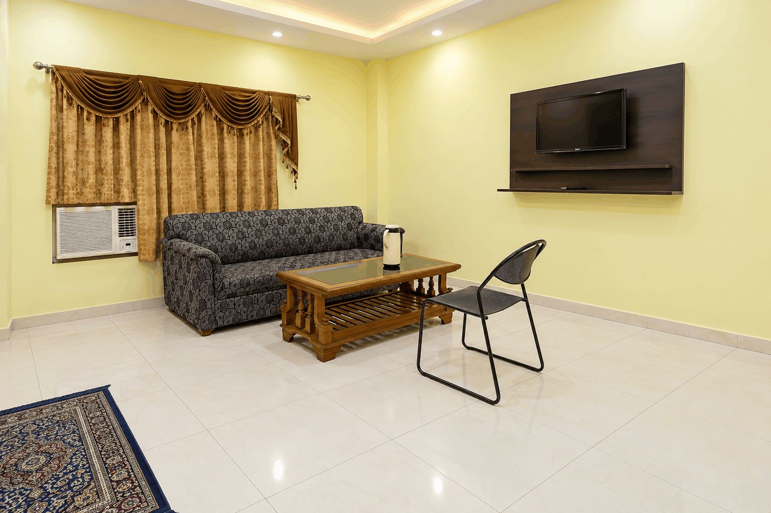 A living room with a sofa, coffee table, and a TV mounted on the wall.