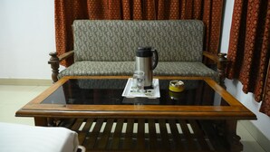 A room with a sofa, a coffee table, and a chair. - Mansarovar Hotel & Banquets (Bareilly)