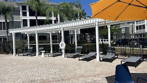 A covered outdoor seating area with lounge chairs and a yellow umbrella. - Crescent Palms - Near Brandon, Tampa, Riverview (Tampa)