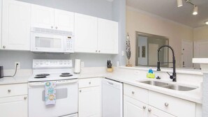 A modern kitchen with white cabinetry, a built-in microwave, a stove, and a sink. - Crescent Palms - Near Brandon, Tampa, Riverview (Tampa)
