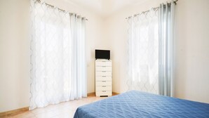 A bedroom with a bed, a dresser, and a TV on top. - Appartamento a Torre Canne con Balcone (Fasano)