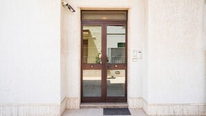 A double door entrance with a metal kick plate, a wall-mounted light fixture above, and a power outlet to the right. - Appartamento a Torre Canne con Balcone (Fasano)