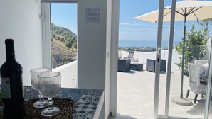 A balcony with a view of the sea, a bottle of wine, and two glasses on a woven mat. - Paradise House in Frigiliana (Frigiliana)