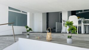 A modern interior with a minimalist design, featuring a staircase, potted plants, and a 'HOME' sign. - Paradise House in Frigiliana (Frigiliana)