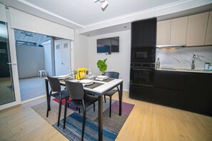Une cuisine moderne équipée d’un four encastré, d’un four à micro-ondes et d’un téléviseur à écran plat fixé au-dessus du plan de travail.