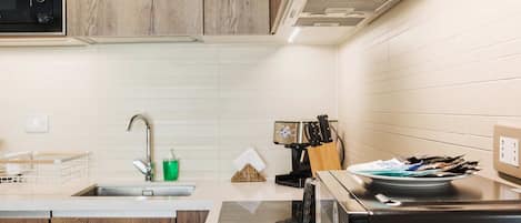 Una cocina moderna con armarios de madera, un lavamanos de acero inoxidable y una estufa negra.