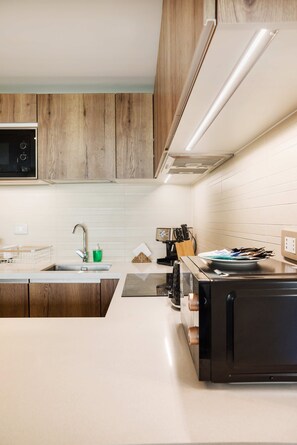 A modern kitchen with wooden cabinets, a stainless steel sink, and a black stove.