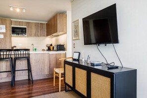 Cocina moderna con gabinetes de madera, microondas, pileta y barra con taburetes.