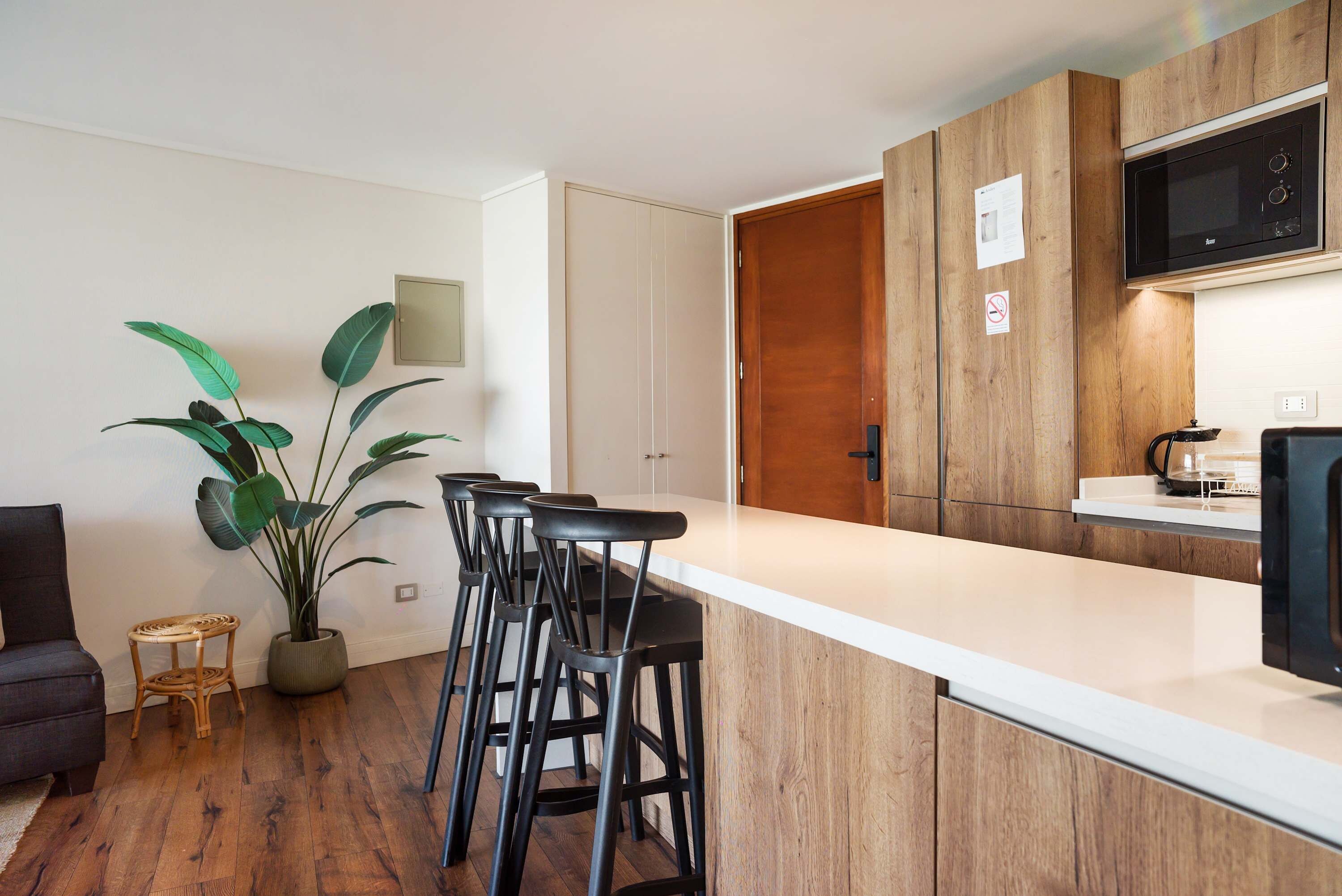A modern kitchen with a wooden cabinet, a white countertop, and a black microwave.