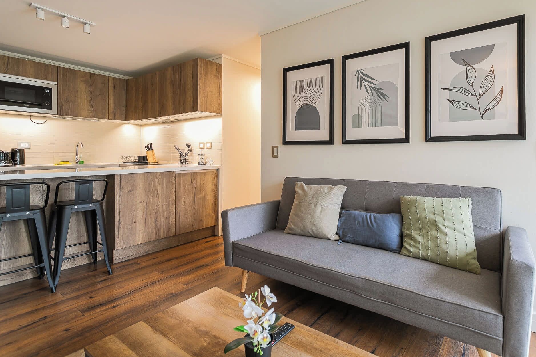 Un espace de vie moderne comprenant une cuisine, un coin bar et un canapé agrémenté de coussins.