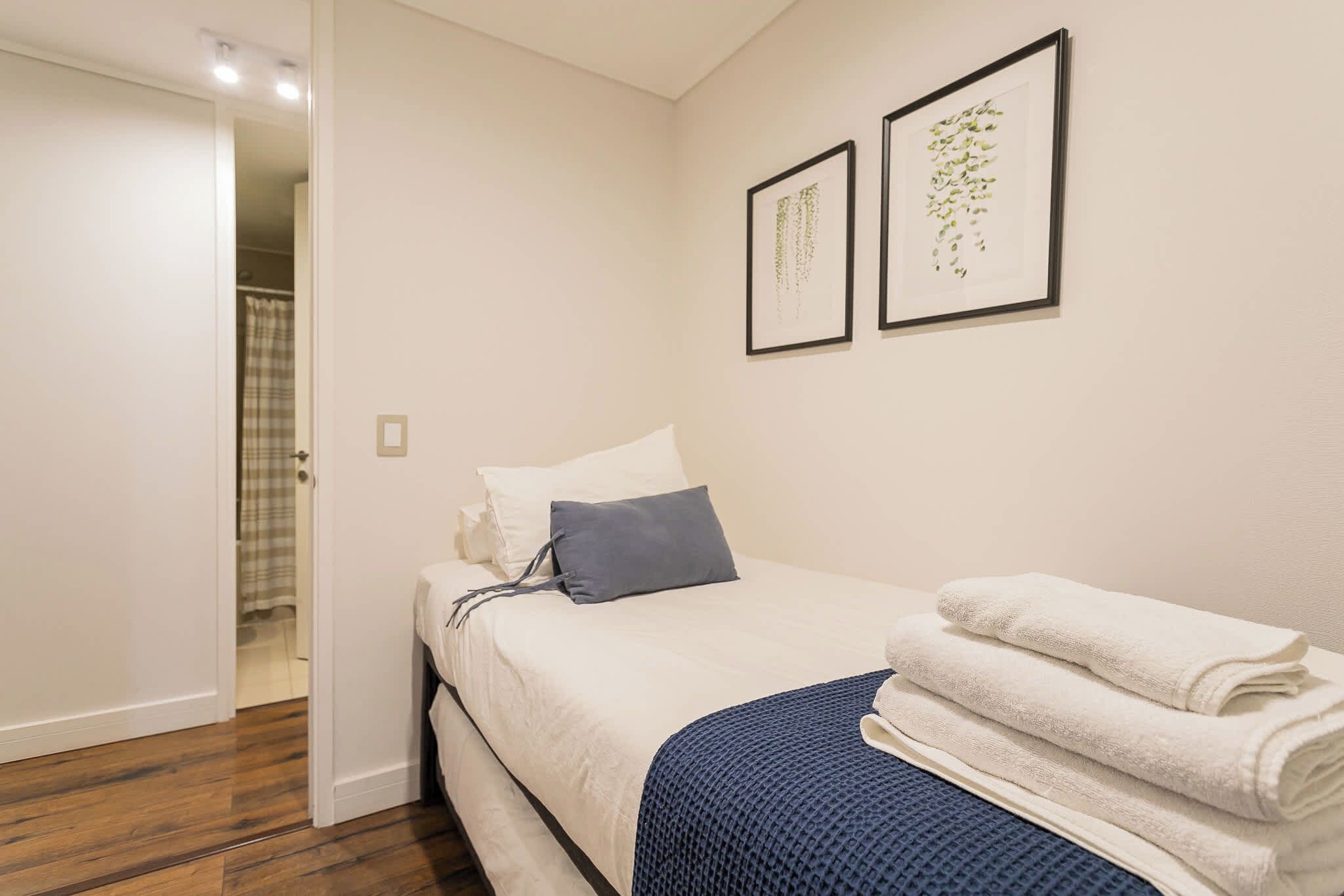 A bedroom with a bed, a door, and two framed pictures on the wall.