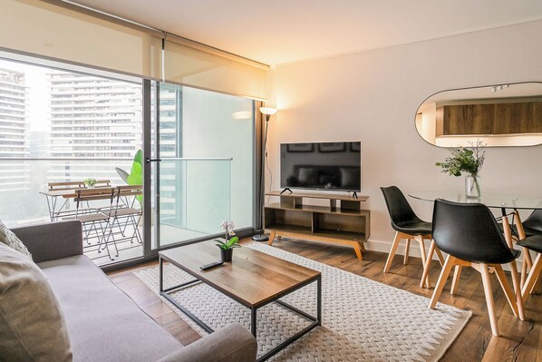 A modern living room with a sofa, coffee table, and dining area with chairs.