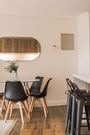 Un comedor moderno con una mesa redonda, sillas negras y un espejo grande.