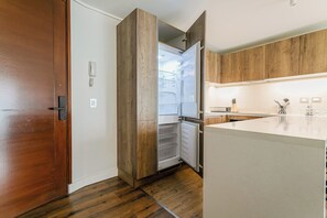 Una cocina moderna con armarios de madera, un refrigerador empotrado y una encimera blanca.
