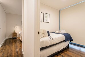 A bedroom with a bed, bedside table, and a wall-mounted shelf.