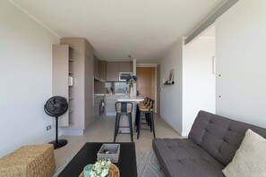 Un salon moderne avec un canapé, une table basse et un ventilateur.