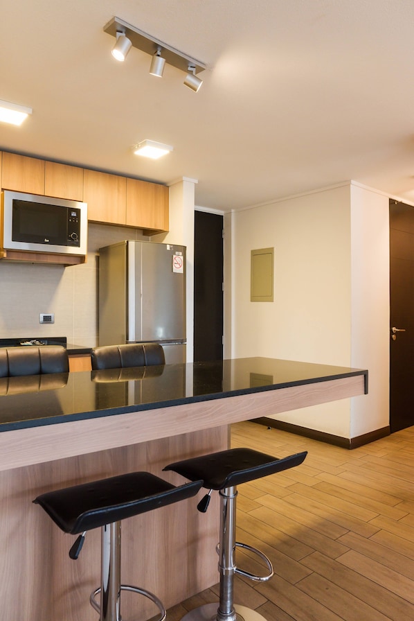 A modern kitchen with a black countertop, stainless steel appliances, and wooden cabinets.