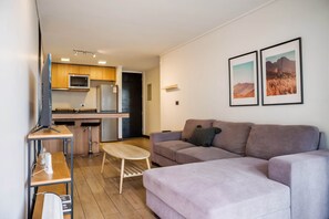 Ein modernes Wohnzimmer mit einer Couch, einem kleinen Tisch und einem Fernseher.
