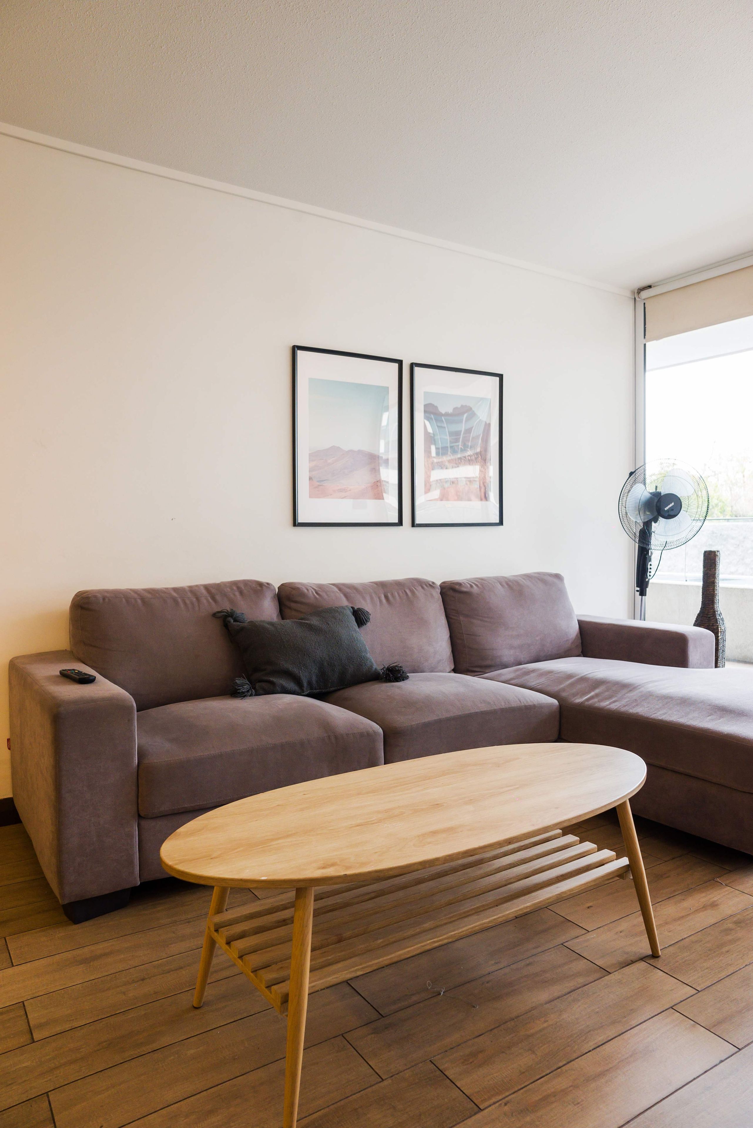 A living room with a brown sofa, a wooden coffee table, and two framed pictures on the wall.