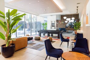 Een moderne lounge met een pooltafel, comfortabele zitplaatsen en grote ramen met uitzicht op het omliggende landschap.