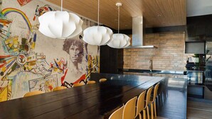 A modern kitchen with a long wooden table and chairs, a brick backsplash, and a graffiti mural on the wall. - Chic Urban Retreat 1BR Apartment in Providencia (Providencia)