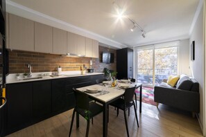 A modern kitchen with a dining area, a flat-screen TV, and a view of the outdoors. - Stylish Urban Studio | Providencia Central View (Providencia)