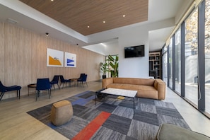 A modern lobby with a wooden wall, a sofa, chairs, a coffee table, and a TV. - Stylish Urban Studio | Providencia Central View (Providencia)
