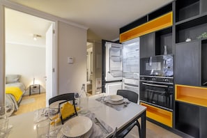 A modern kitchen with a built-in oven, a refrigerator, and a dining area with a table set for two.