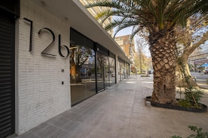 A building with a white brick facade, large glass windows, and a palm tree in the foreground. - Stylish Urban Studio | Providencia Central View (Providencia)