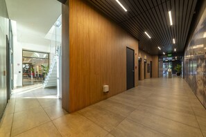 A modern hallway with a wooden wall, a glass door entrance, and a sign indicating the exit.