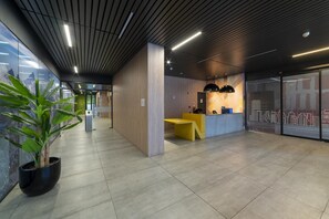 A reception area with a modern design, featuring a reception desk, a large potted plant, and a glass wall with a cityscape mural. - Stylish Urban Studio | Providencia Central View (Providencia)