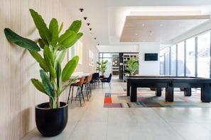 Un espace intérieur moderne doté d’une table de billard, d’un coin salon et de grandes fenêtres.