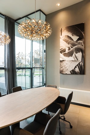 Une salle de conférence moderne, dotée d’une grande table ovale, de chaises de bureau noires et d’une grande fenêtre donnant sur l’extérieur.