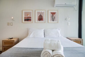 A hotel room with a large bed, two bedside tables, and three framed artworks on the wall.