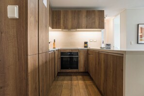Een moderne keuken met houten kastjes, een inbouwoven en een aanrecht.