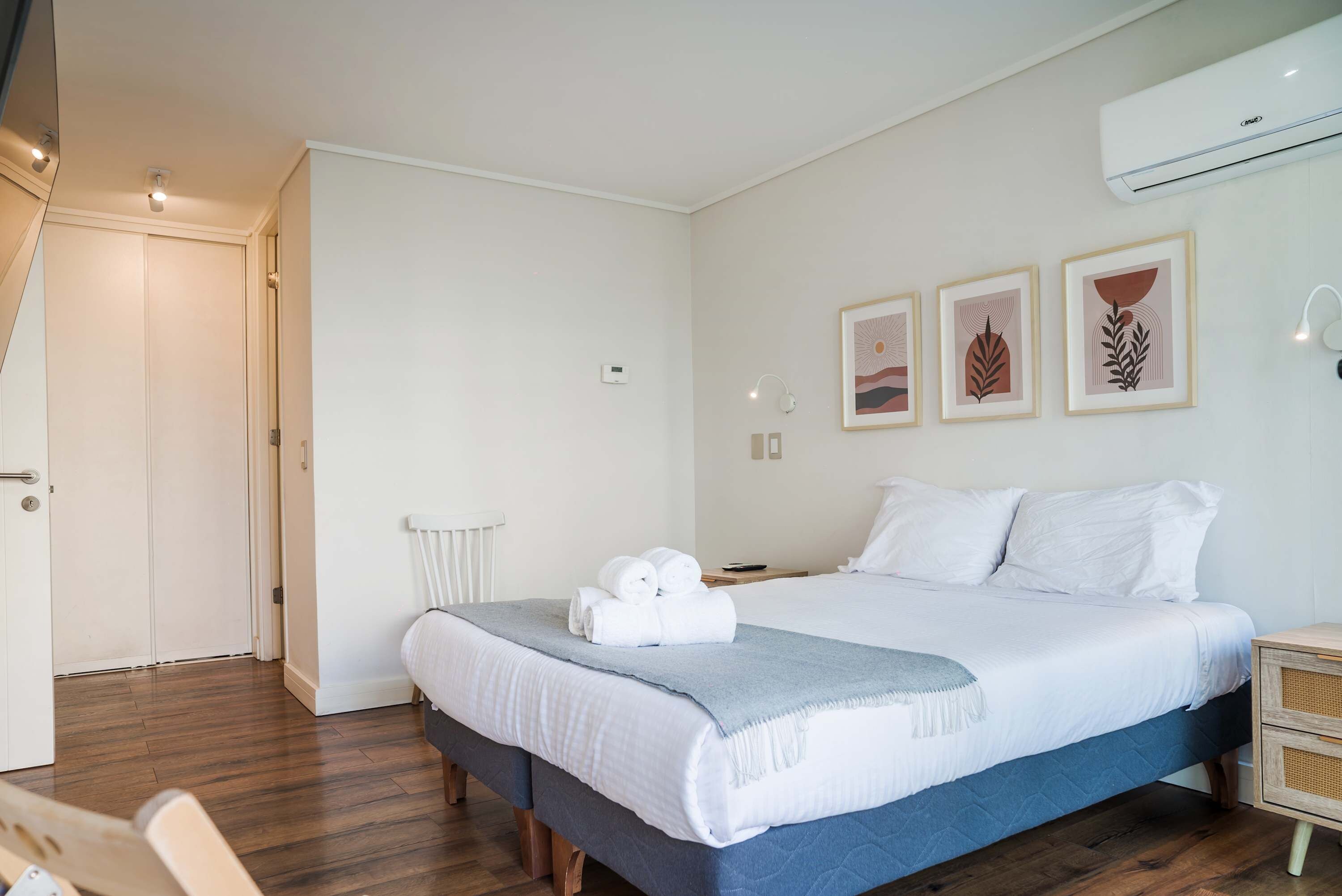 A bedroom with a bed, a bedside table, a chair, a radiator, and a door.