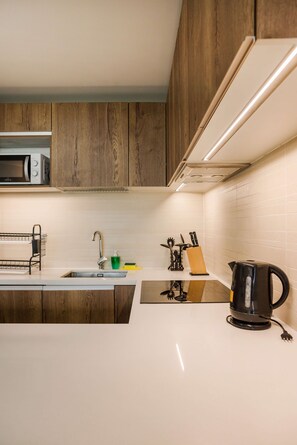 A modern kitchen with wooden cabinets, a stainless steel sink, and a black kettle.