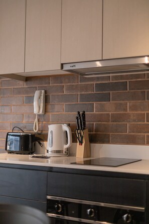 A kitchen with a brick backsplash, a coffee maker, a kettle, a knife block, and a phone. - Charming Studio Retreat in Providencia's Heart (Providencia)
