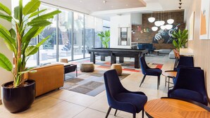 A modern lounge area with a pool table, comfortable seating, and large windows offering a view of the outdoors. - Charming Studio Retreat in Providencia's Heart (Providencia)