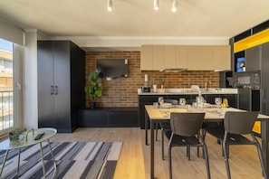 A modern kitchen with a brick backsplash, a dining area with a table set for two, and a small balcony with a view. - Charming Studio Retreat in Providencia's Heart (Providencia)