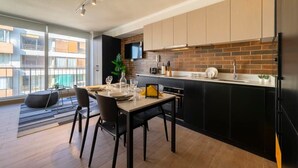 A modern kitchen with a dining area, large windows, and a brick backsplash. - Charming Studio Retreat in Providencia's Heart (Providencia)