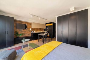 Una habitación moderna con una cama, un escritorio, una silla, una mesita y un televisor montado en la pared.