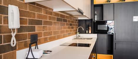 Una cocina moderna con salpicadero de ladrillo, encimera blanca y refrigerador negro.