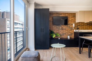 A modern kitchen with a brick wall, a flat-screen TV, and a small dining area with a table and chairs. - Stylish and Cozy Studio Apartment in Providencia (Providencia)