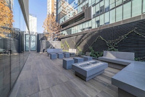 Un espace extérieur aménagé avec des meubles modernes, un foyer et une vue sur le paysage urbain.