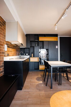Een moderne keuken met een centraal eiland, een eettafel met stoelen en een inbouwoven.