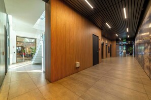 Un couloir moderne avec un lambris en bois, une entrée en verre et un sol carrelé.